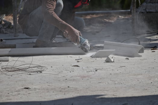 A worker is using a tool to cut cement rods. causing dust to permeate concept of safety at work photo