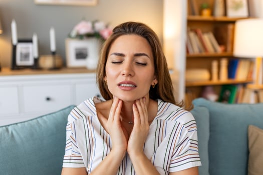 Close up of young woman rubbing her inflamed tonsils, tonsilitis problem, cropped. Woman with thyroid gland problem, touching her neck, girl has a sore throat photo