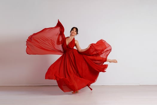 Dancer in a red flying dress. Woman ballerina dancing on a white studio background photo