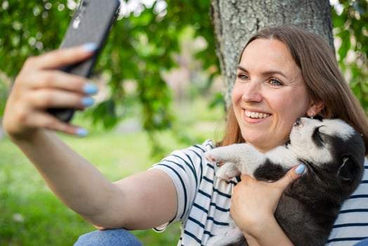 Woman in a t-shirt and jeans with a husky puppy takes a photo or selfie