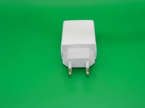 Macro photo of the white charging head on a green background. Usually use for smartphone