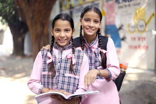 With A Book In Her Hands Small Village Girls Looking At Each Other And Smiles photo
