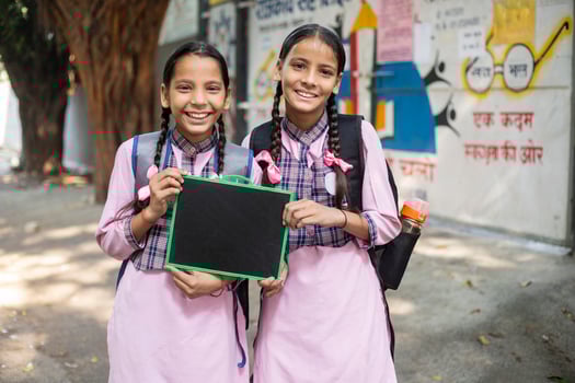 Portrait Of Cute Indian Girls Sitting And Hugging Each Other In Park While Posing In Front Of Camera photo