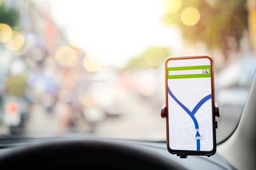 The map on the phone in the background of the dashboard. Black mobile phone with map gps navigation fixed in the mounting. photo
