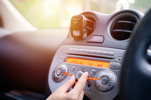 Women turning button on car radio for listening to music photo