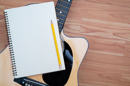 Acoustic guitar concept, the guitar body pattern is wood grain. Notebook and yellow wooden pencil photo