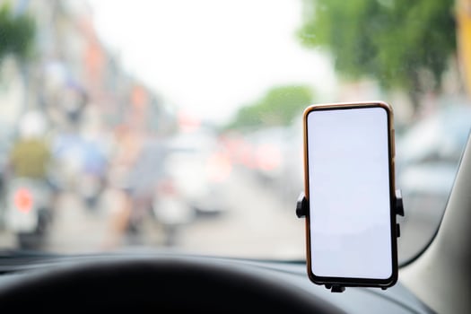 Smartphone in a car use for Navigate or GPS. Driving a car with Smartphone in holder. Mobile phone isolated white screen. Blank empty screen. copy space. Empty space for text. car interior details. photo