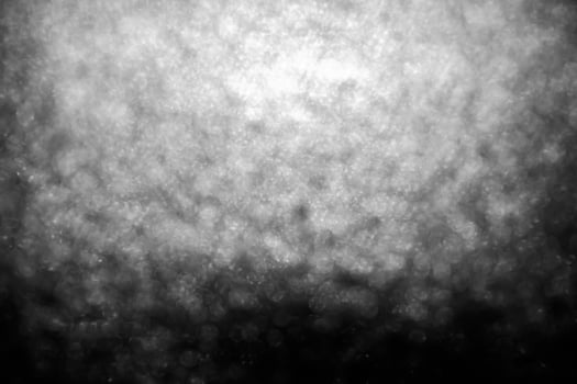 Bokeh lights on black background, shot of flying drops of water in the air, defocused water drops levitation on dark, blurred photo