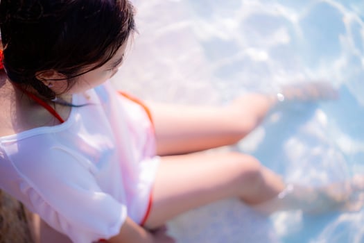 Top view beautiful young woman posing by the pool in tropical resort photo