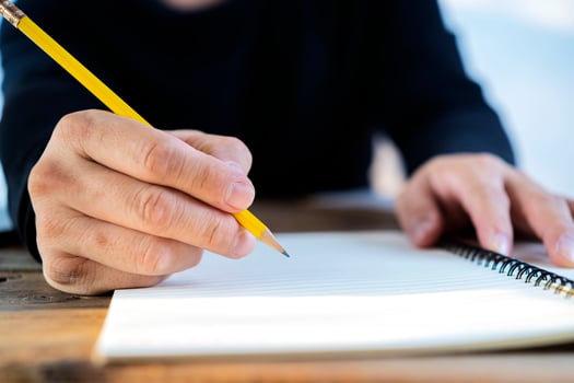 Closeup cropped hands of man writing day plan in notebook at the workplace at the computer. photo