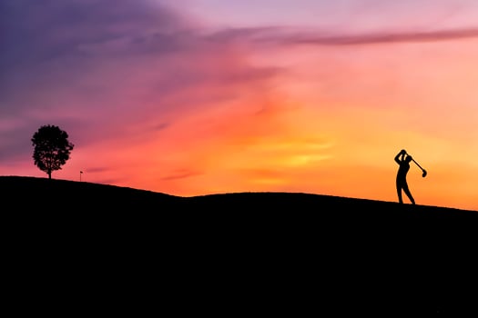 silhouette golfer hitting golf shot on sunset, in the summer for relax time photo