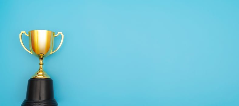 Simply flat lay design winner or champion gold trophy cup isolated on blue pastel colorful background. photo