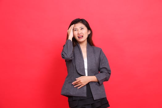 expression of asian office girl holding head dizziness and candid headache wearing gray jacket and red background skirt. for health, business and advertising concepts photo