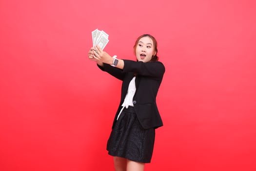 gesture of mature Asian office girl surprised and happy wearing a black formal suit, both hands holding dollar bills in front of the right, for corporate content, fashion, advertising, broadcasts photo