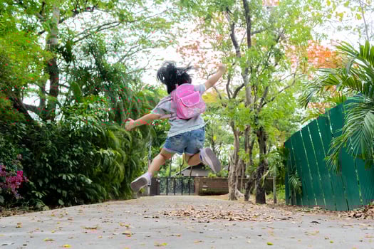 Back to school. Cute asian child girl with backpack running photo