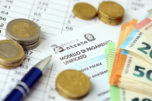 KYIV, UKRAINE - APRIL 20, 2024 Agenzia Entrate logo from blank tax form and many euro banknotes on office table photo