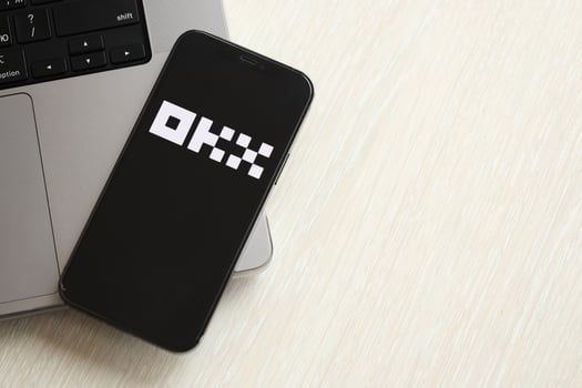 KYIV, UKRAINE - MARCH 15, 2024 OKX logo on iPhone display screen on MacBook panel photo