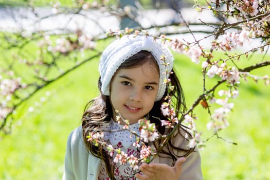 Portrait of a little girl in the flowering branches of a spring tree photo