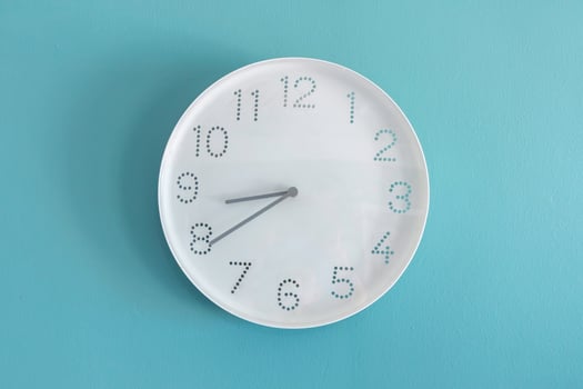 A white wall clock on blue wall. Analog clock. photo
