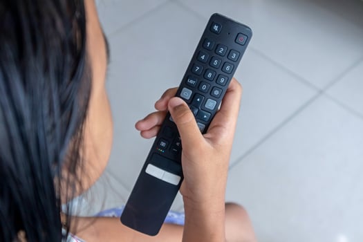 A little Asian girl holding TV remote control directed on the television inside the room photo