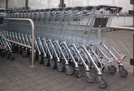 Metal grocery carts stand in a store parking bay photo