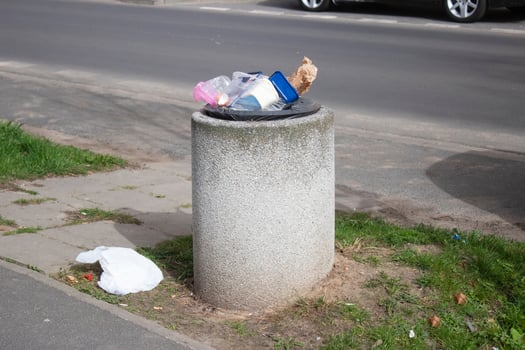 Public trash can on a city street filled with garbage photo