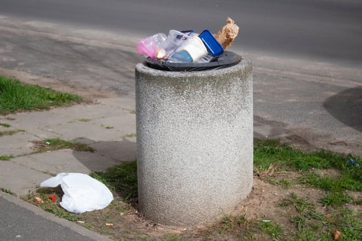 Public trash can on a city street filled with garbage photo