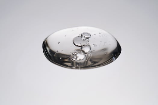 A drop of cosmetic product with bubbles on a gray background. photo