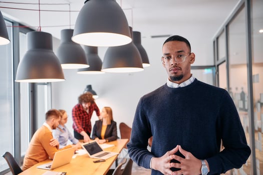Startup Leadership. African American Businessman in Modern Office with Colleagues in Background. photo