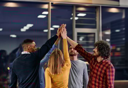 Overjoyed young multiethnic businesspeople have fun celebrate shared business success or victory in office. Smiling multiracial diverse employees feel excited win get good results. Teamwork concept photo