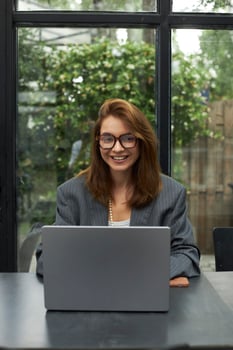 Young woman in eyeglasses working with laptop while sitting at cafe photo