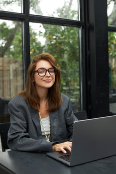 Young woman in eyeglasses working with laptop while sitting at cafe photo
