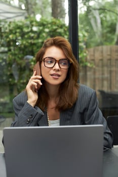 Young woman in eyeglasses working with laptop while sitting at cafe photo