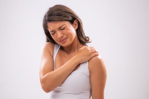 Portrait of adult woman who is having sprain in her shoulder. photo