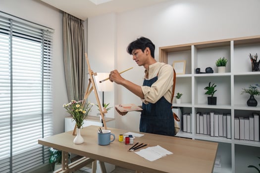 Young Artist Painting on Canvas in Modern Home Studio with Natural Light and Indoor Plants photo