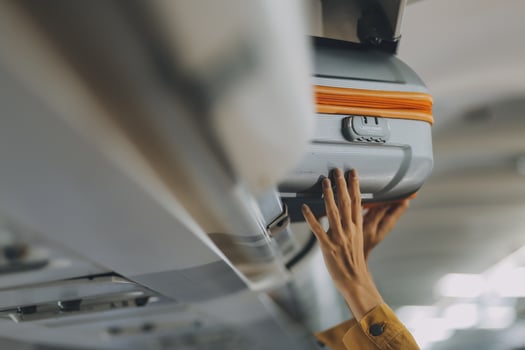 Young Female Tourist Storing Luggage in Overhead Compartment on Airplane During Travel photo