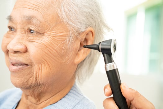 Audiologist or ENT doctor use otoscope checking ear of asian senior woman patient treating hearing loss problem. photo