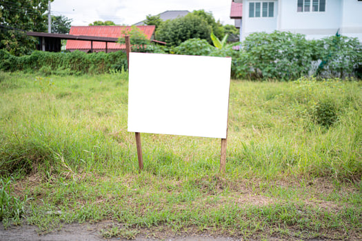 Blank white empty mockup template of a real estate sign at front of a lot of vacant lan photo