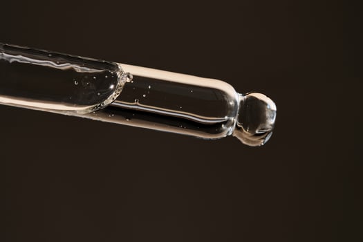 Pipette with serum on a dark beige background. photo