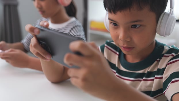 Asian kids play online games with friends on mobile phones for fun at home. photo