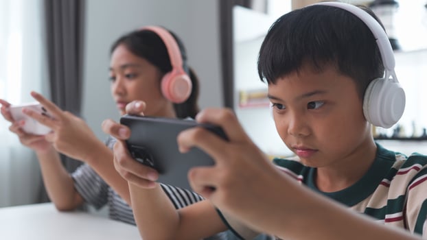 Asian kids play online games with friends on mobile phones for fun at home. photo