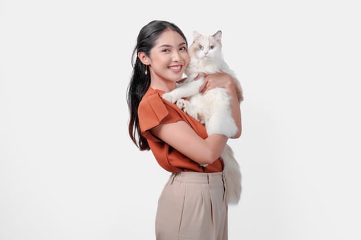 Cute young Asian woman in brown shirt is holding a white ragdoll cat and hugging it. photo