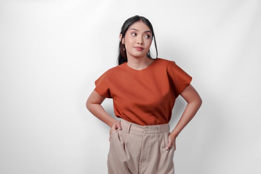 Attractive young Asian woman in brown shirt and taupe pants smiling and posing to the camera, isolated by white background. photo