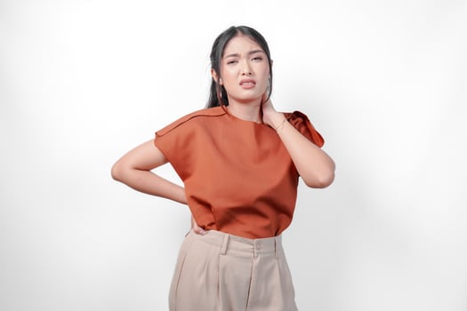 Tired young Asian woman in a brown shirt suffering from pain, muscle spasm on the neck isolated white background. photo