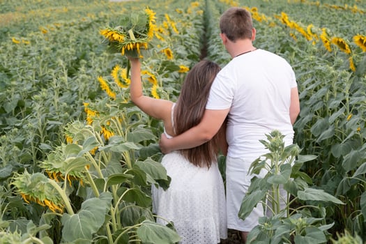 Cheerful couple in sunflowers in field at sunset photo