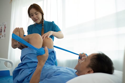a woman in a blue uniform helps a man in a hospital bed photo