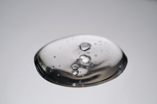 A drop of cosmetic product with bubbles on a gray background. photo