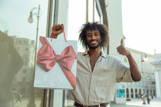 A man goes shopping and is happy, he gives the thumbs up with the shopping bag photo