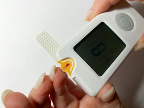 Measurement of blood sugar levels using a glucose meter with a mock-up. Piercing a finger to draw blood photo