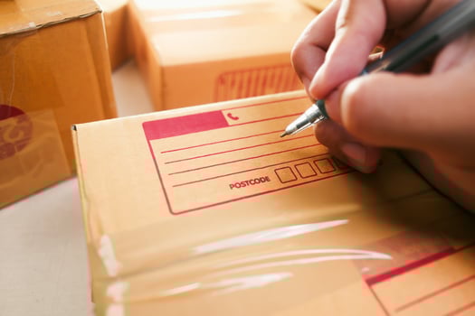 Goods delivery concept Human hand writes an address on a cardboard box for delivery to a customer photo